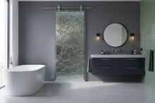Private sliding glass barn door in a modern bathroom, handcrafted by Sans Soucie Art Glass for premium privacy and artistic texture.