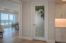 Interior door with glass panel ideas for modern interiors. Frosted glass interior door with etched coastal wave design in a clean, modern beach house, allowing soft light while adding privacy and ocean-inspired style.