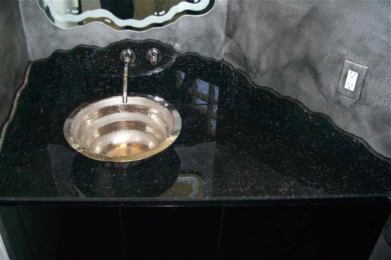 It's difficult to appreciate the beautiful effect in this black, shattered glass vanity.  The photo doesn't show the sparkling, beautiful details enough.  The vessel is a polished steel.  The backsplash is chiseled irregular and we did a mirror above to compliment that features a carved texture around the irregular edge border.