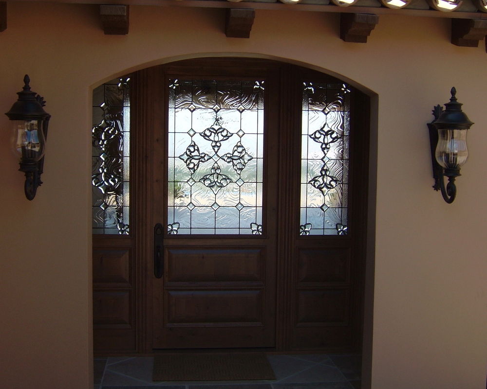 Wood front door with decorative stained beveled glass panels and matching sidelights in an arched entryway