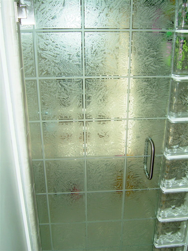 Textured frosted glass shower door with square grid design and metal handle