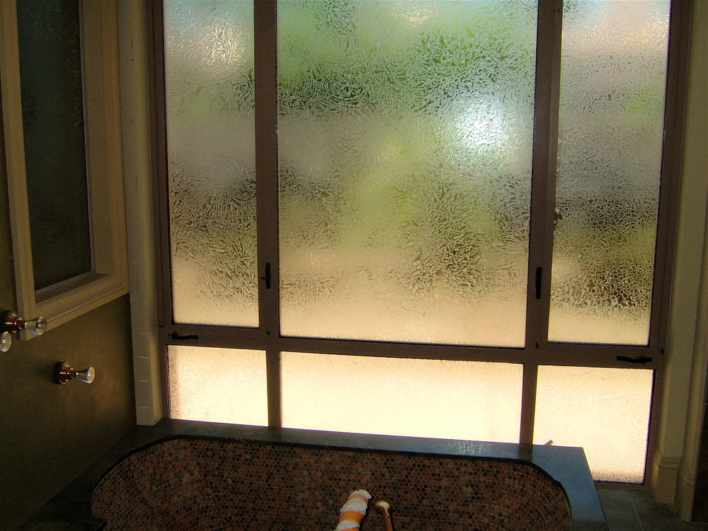 Shower with window featuring textured glue chip privacy glass panels above a bathtub in a traditional bathroom
