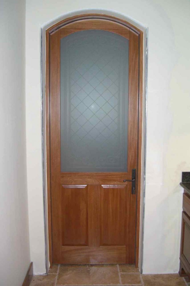 Traditional wood front door with an arched frosted glass panel featuring a subtle diamond pattern for added privacy.