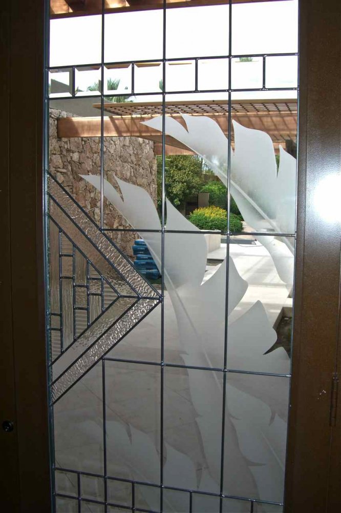 close-up of etched glass front door panel with geometric pattern and frosted palm leaf design providing privacy and light