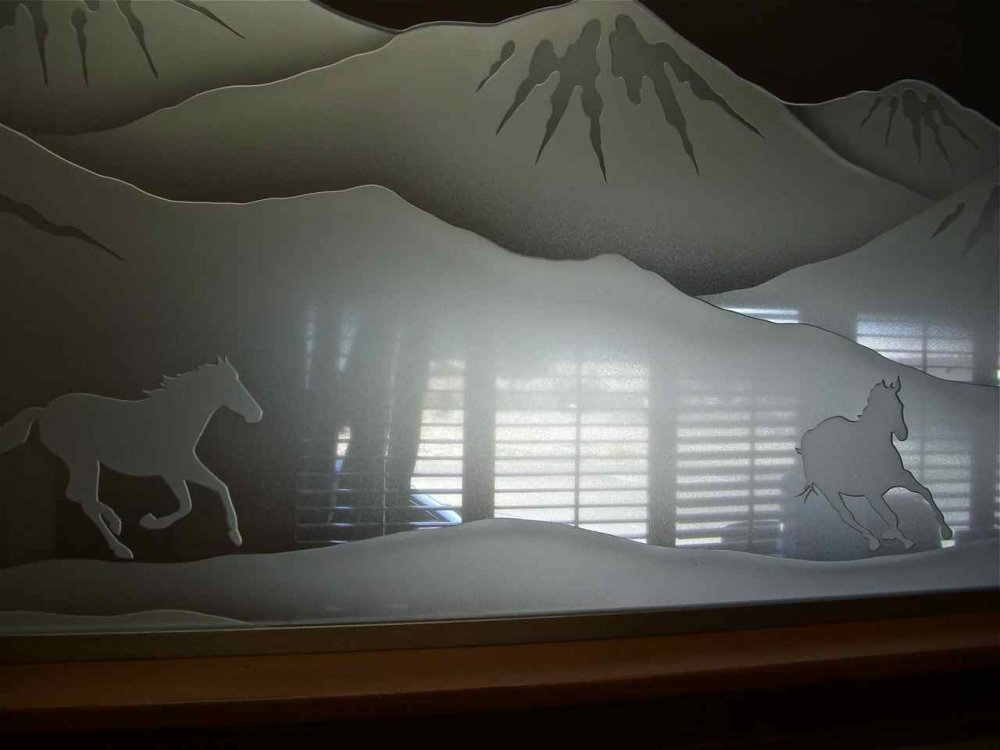 Decorative glass partition panel with mountain scenery and running horses, showcasing custom frosted glass room divider art inspired by western landscapes.