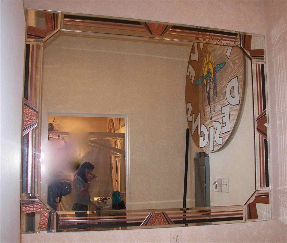 Decorative mirror glass art with carved geometric border in bathroom setting