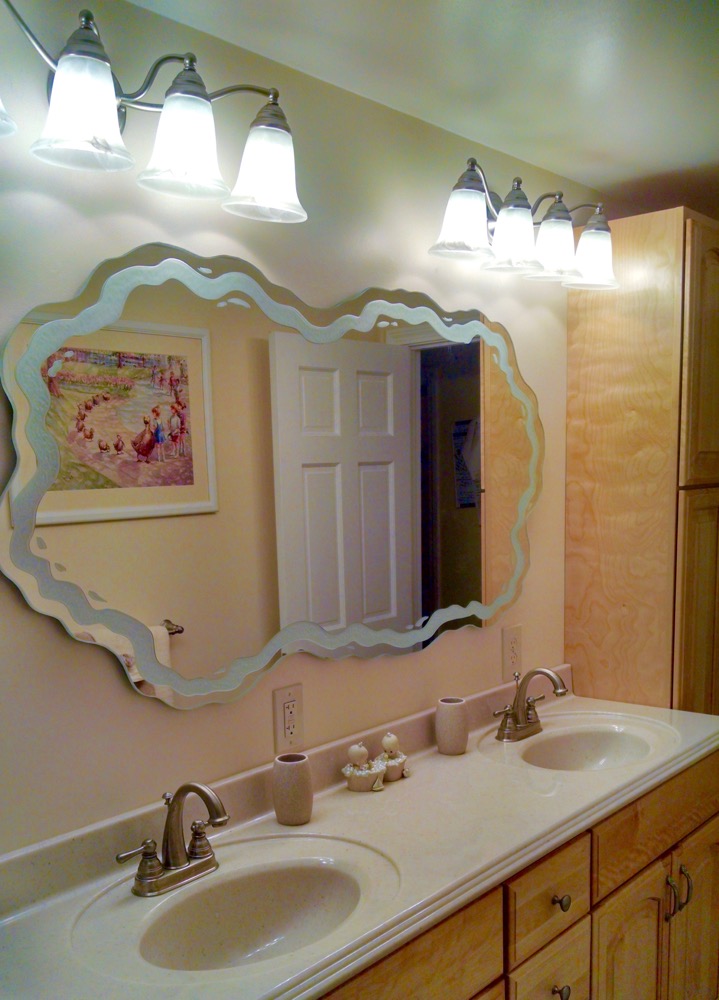 Free-flow glass decorative mirror art with sculpted etched edge above double bathroom vanity