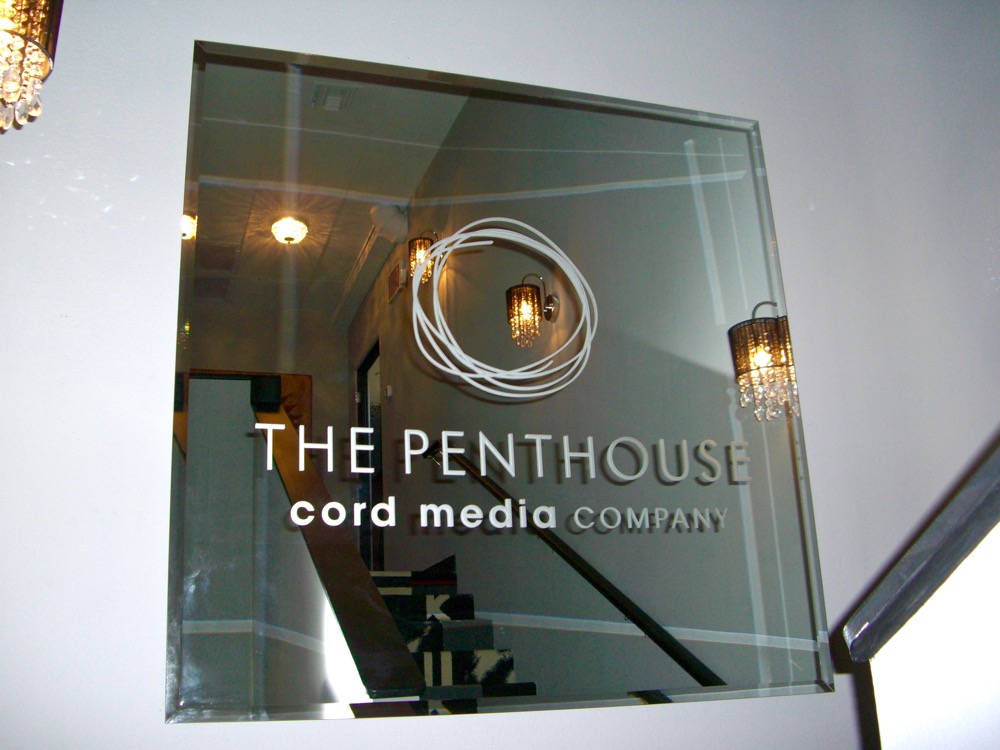 Custom etched glass mirror office sign with company logo and business name, creating a sleek and professional branded interior environment