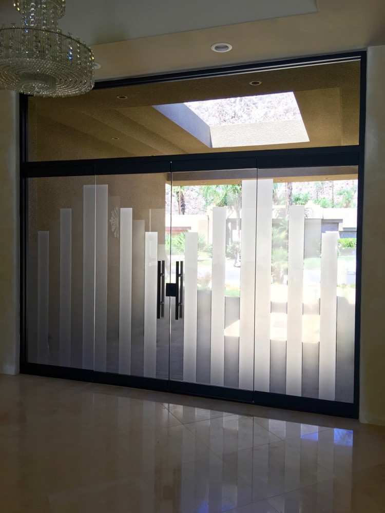 Frosted glass entry doors viewed from inside with no interior lights on and strong daylight behind the glass, creating a bright glowing appearance