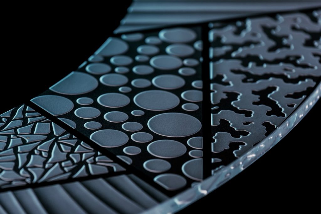 close-up of carved glass tabletop showing detailed etched textures and circular pattern design in frosted glass