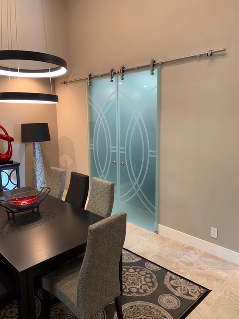 Frosted glass barn doors installed in conference space, modern glass barn door pair with decorative etched pattern and sliding track system
