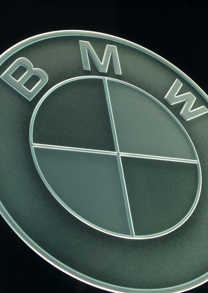 Decorative glass sign with BMW logo, etched and carved glass branding signage with dimensional frosted design