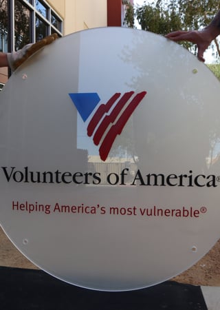 Glass Sign featuring a Frosted Glass Logos Design Sandblast Etched Glass Volunteers of America (similar look) Design by Sans Soucie