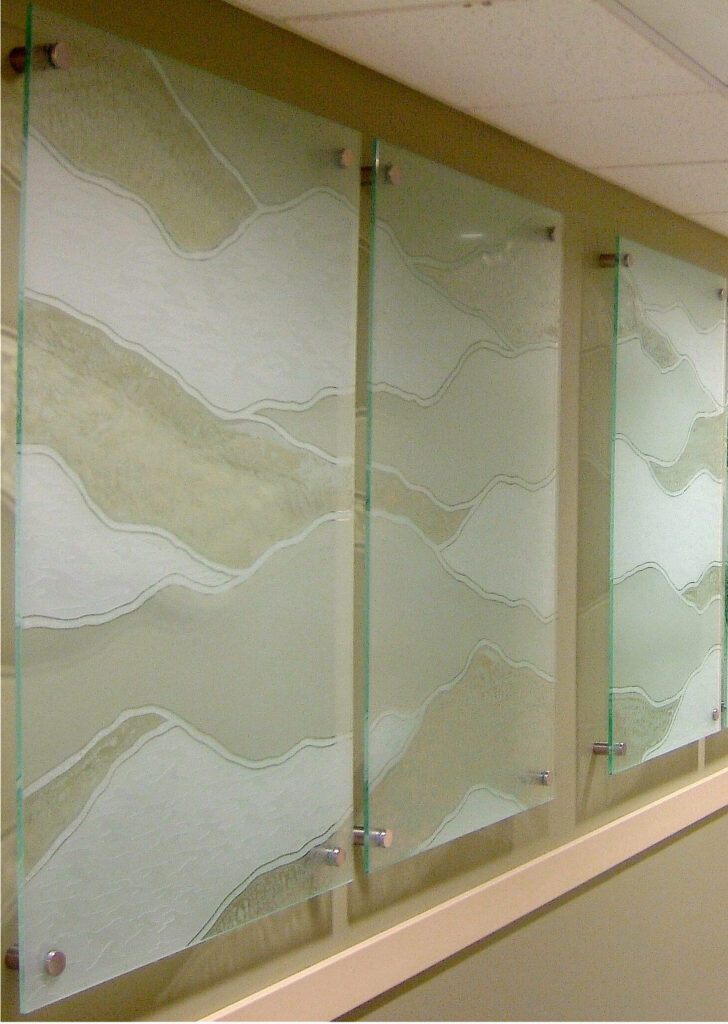 Decorative glass wall partition panels with layered abstract landscape patterns etched into frosted glass