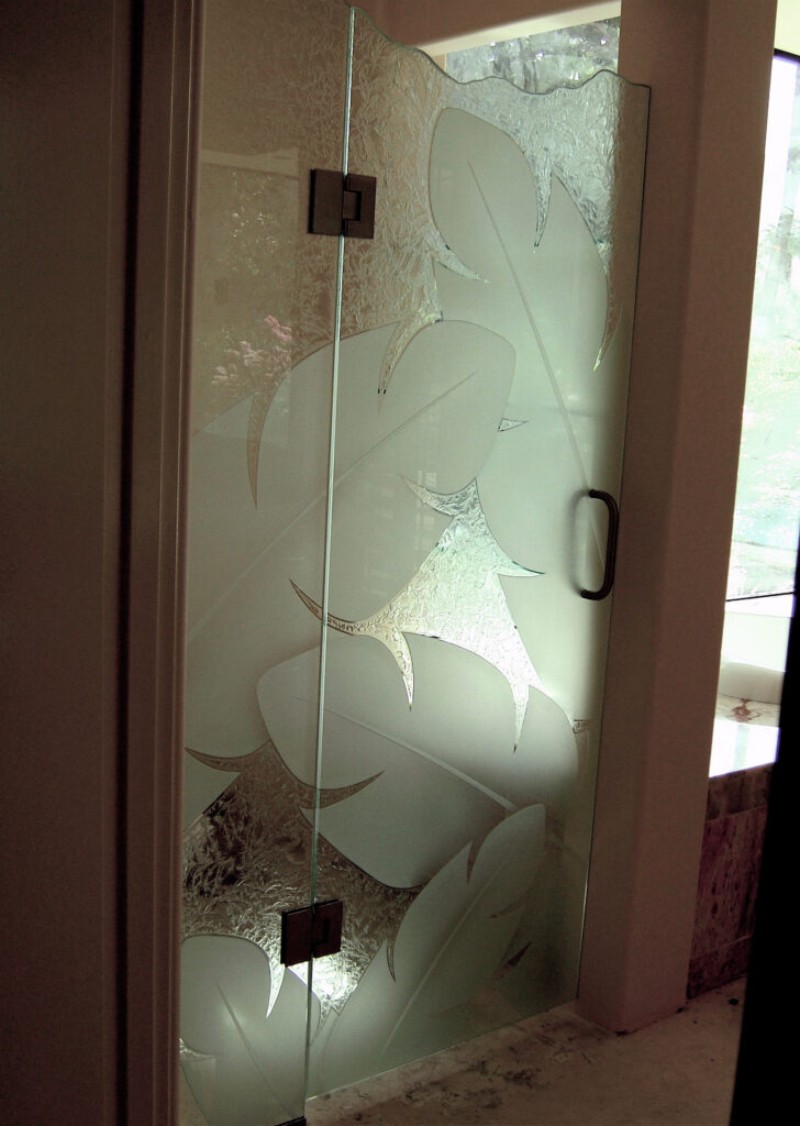 Nature inspired frosted glass shower door with 3D carved designs.
