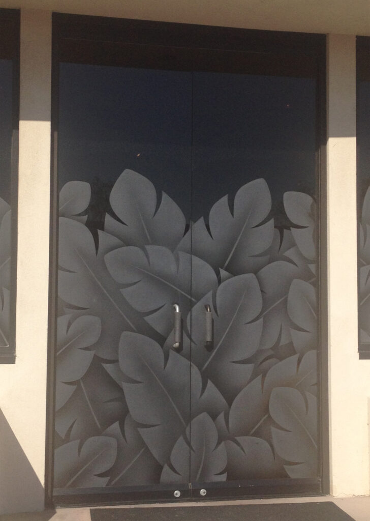 Frameless glass double doors with large tropical banana leaf pattern