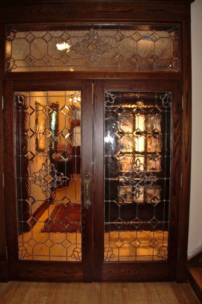 Classic wood double doors featuring decorative leaded beveled glass panels and matching transom window