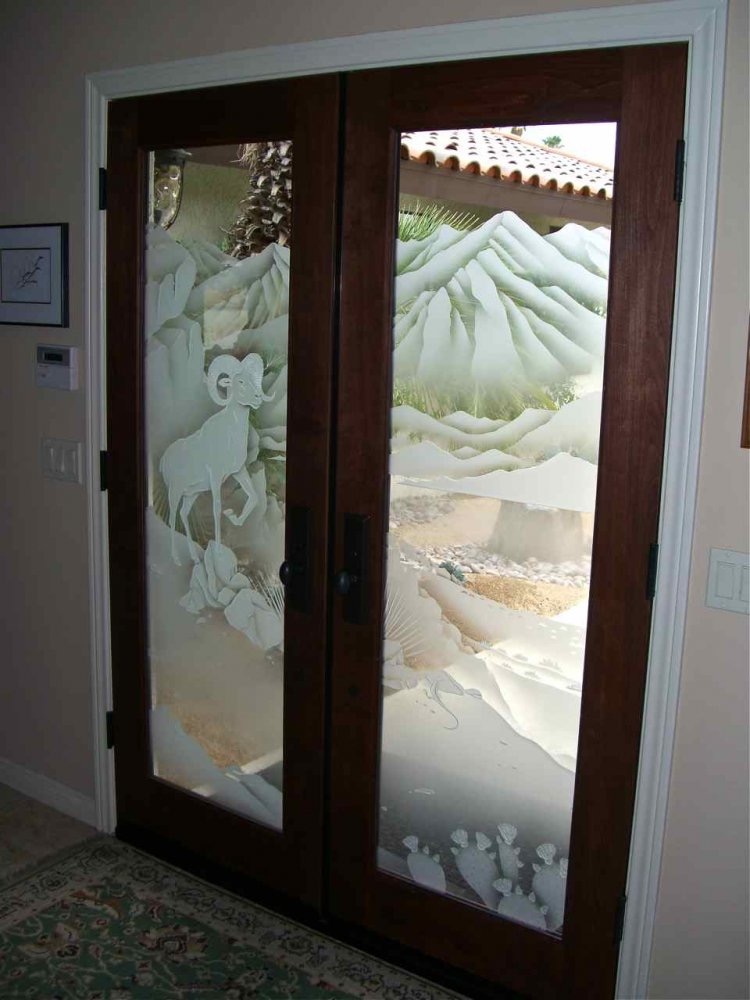 Frosted carved glass door with bighorn sheep design, viewed from inside with interior lights on and natural daylight outside