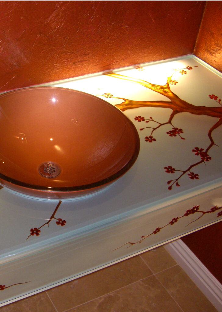 custom carved and painted glass countertop with cherry blossom design illuminated from below with edge lighting