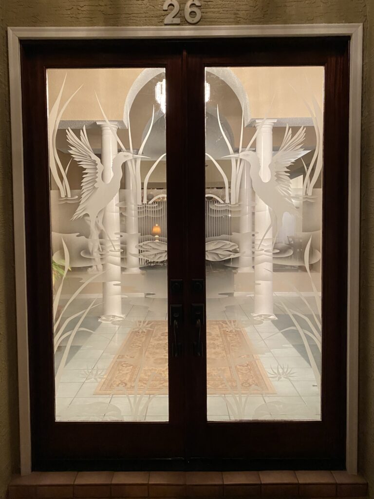 Pair of front doors with decorative frosted glass featuring crane design, combining clear and frosted areas for layered semi-privacy and artistic detail