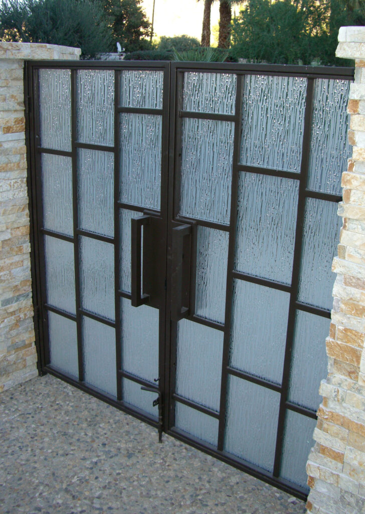 Modern glass entry gate with textured frosted glass inserts and black metal framing, providing privacy and contemporary architectural style.
