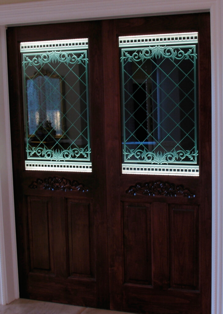 edge-lit carved glass door panels with decorative lattice and scroll design illuminated with soft LED lighting