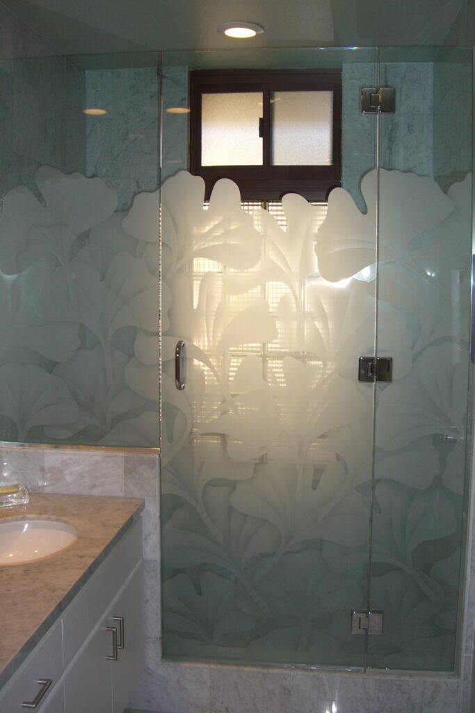 Frameless glass shower door with frosted gingko leaf design sandblasted into tempered glass for privacy and natural light