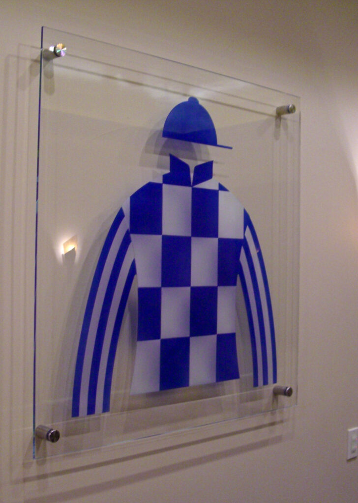 custom carved glass signage with jockey jersey design mounted on clear glass panel with standoff hardware