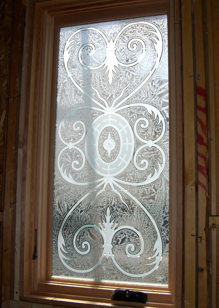 Custom small bathroom window with frosted and etched glass detailing for a modern look.