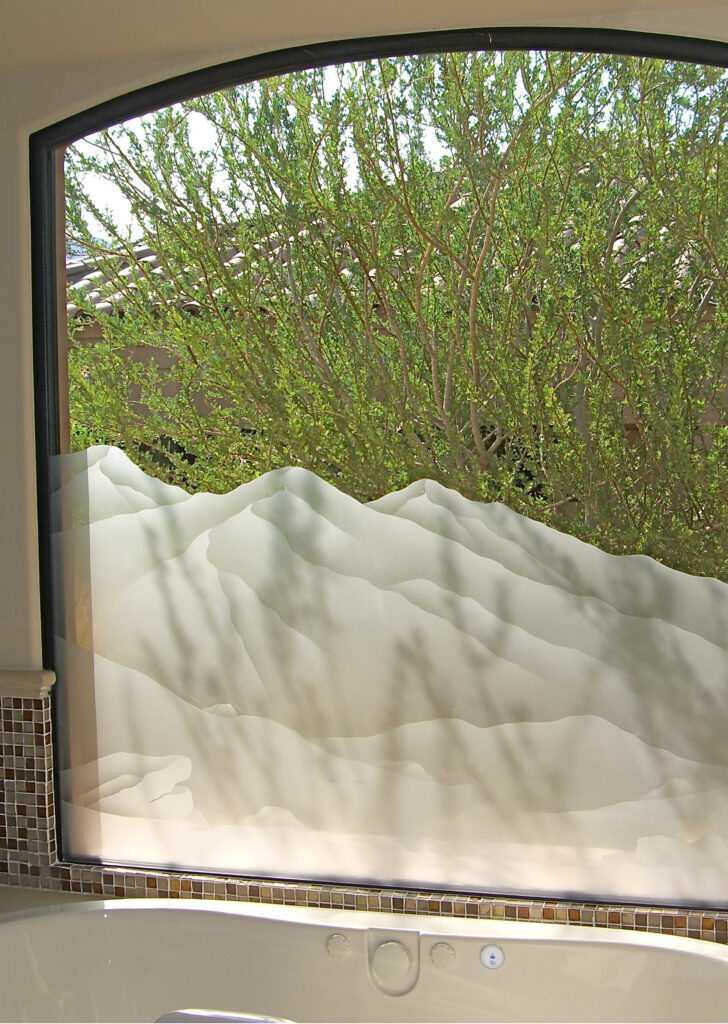 Custom etched frosted glass Mountains design used in stationary windows, providing privacy and natural light above a bathtub