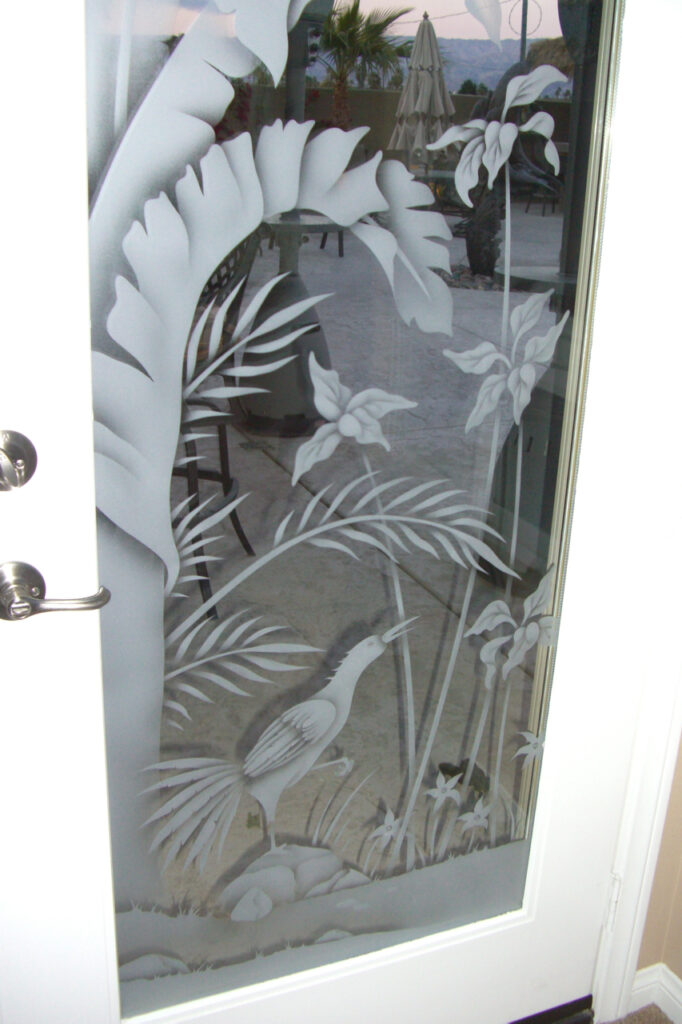 Frosted glass door with sandblasted tropical bird, palm leaves, and flowers in a decorative etched glass panel