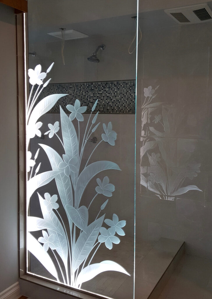edge-lit carved glass shower divider with frosted floral design featuring plumeria flowers and glowing illuminated edges for privacy