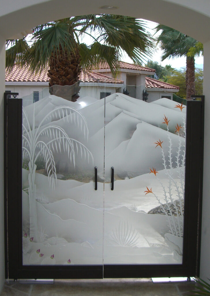 Custom etched glass entry gate featuring a desert landscape with palm trees, mountains, and frosted privacy glass in a decorative glass entry gate.