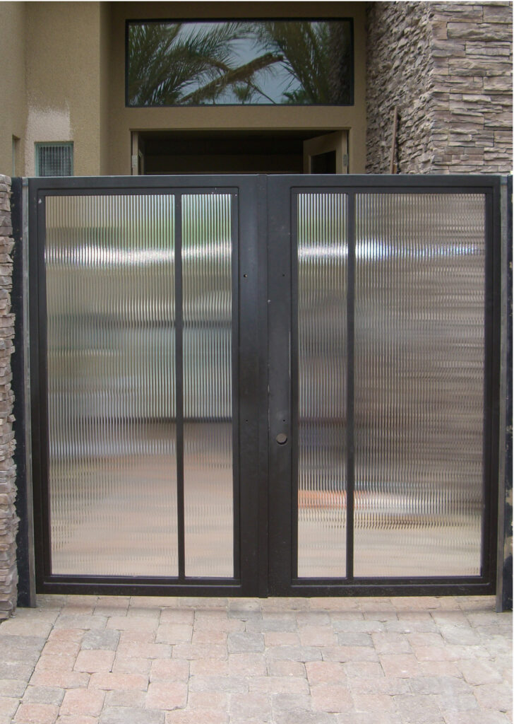 Modern glass entry gate with reeded glass inserts and black metal frame, providing privacy and architectural appeal.