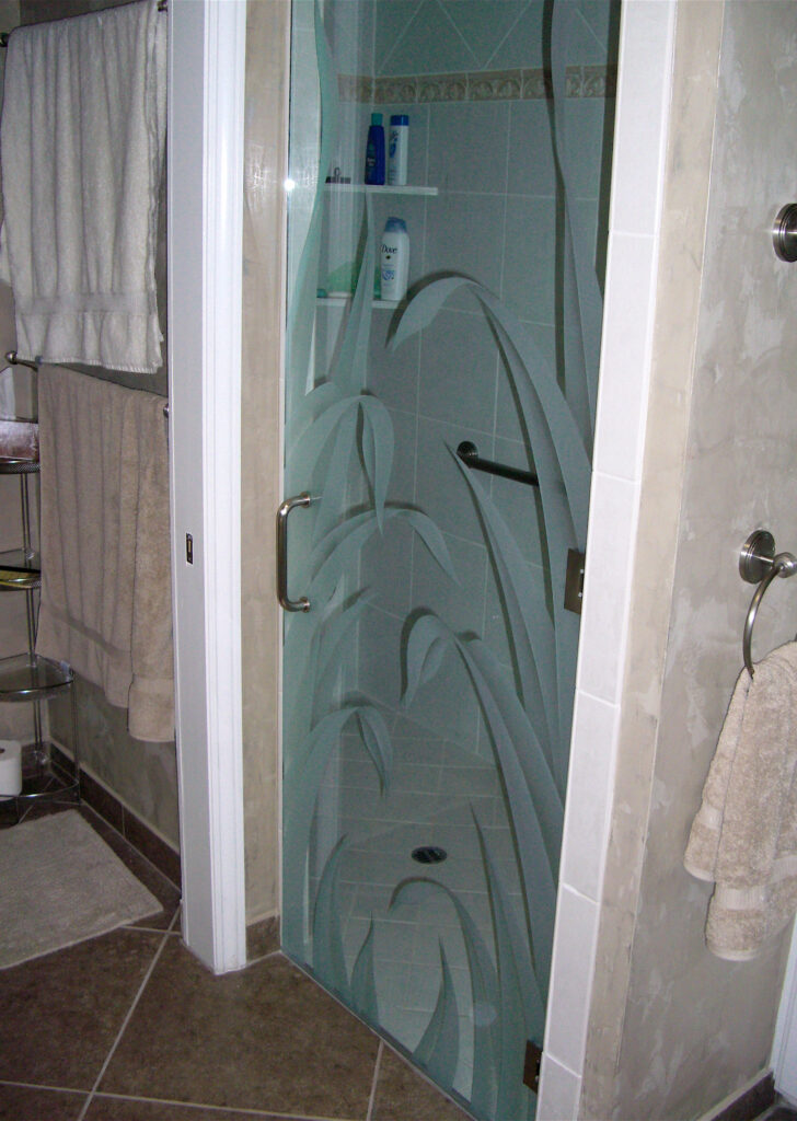 Frameless glass shower door with a carved reeds design, adding privacy and organic style to a bathroom shower entrance.