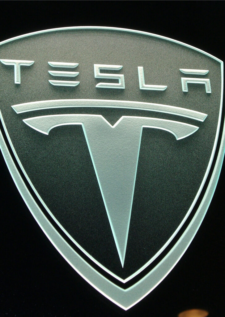 Carved and etched glass logo sign displayed against dark background, highlighting strong contrast and creating a bold, professional brand statement