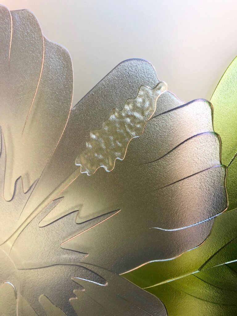 Close-up view of an exquisite 3D carved frosted glass design featuring detailed hibiscus and anthurium flowers.