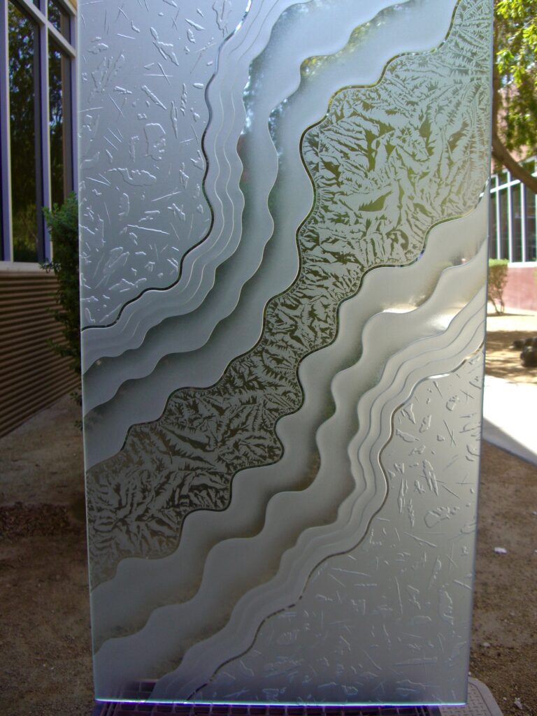 Close-up of layered carved and frosted glass design Metamorphosis Peak with flowing contours, a sophisticated design for a black front door with glass panels that adds privacy and modern elegance.