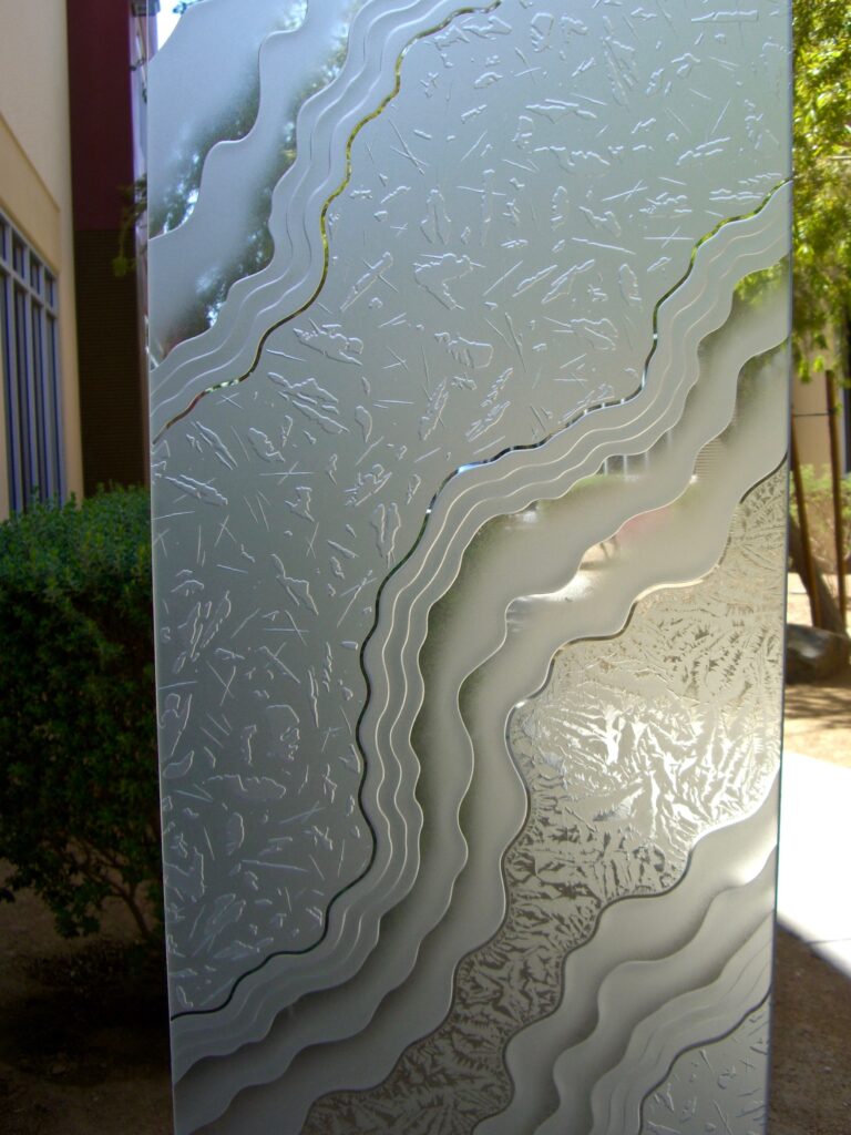 Detailed view of Metamorphosis Peak, a carved and etched frosted glass with layered contours, perfect for a black front door with sidelights that delivers depth, texture, and controlled light.
