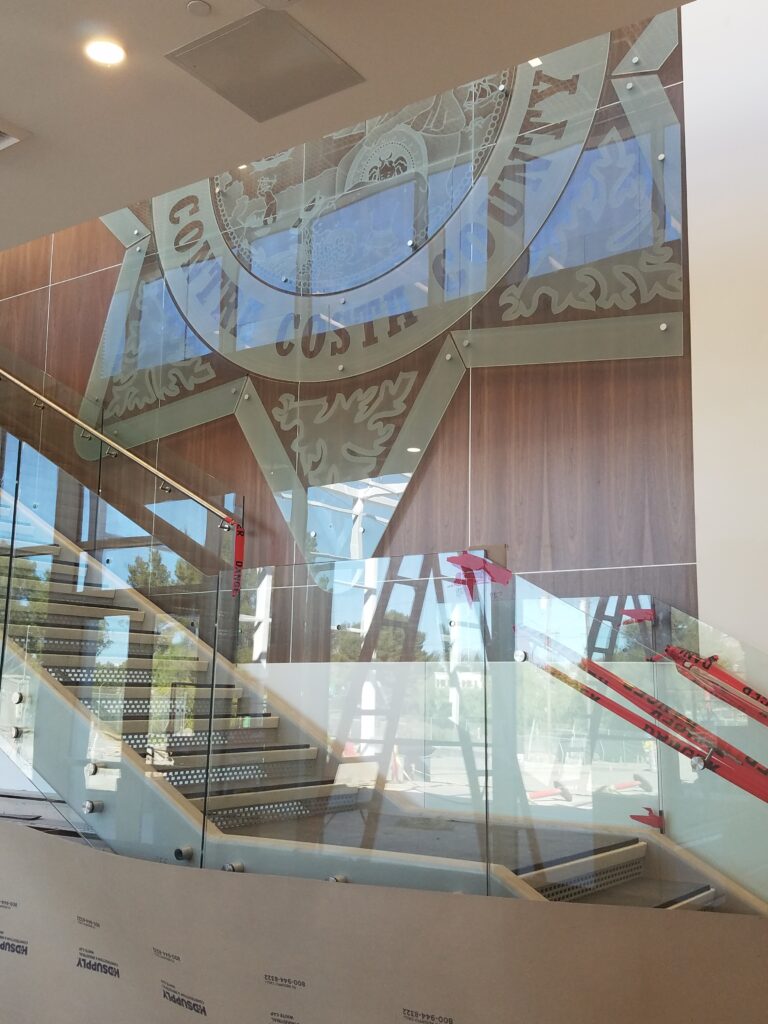 Decorative etched glass panels forming a large wall feature, custom architectural glass signage integrated into interior design