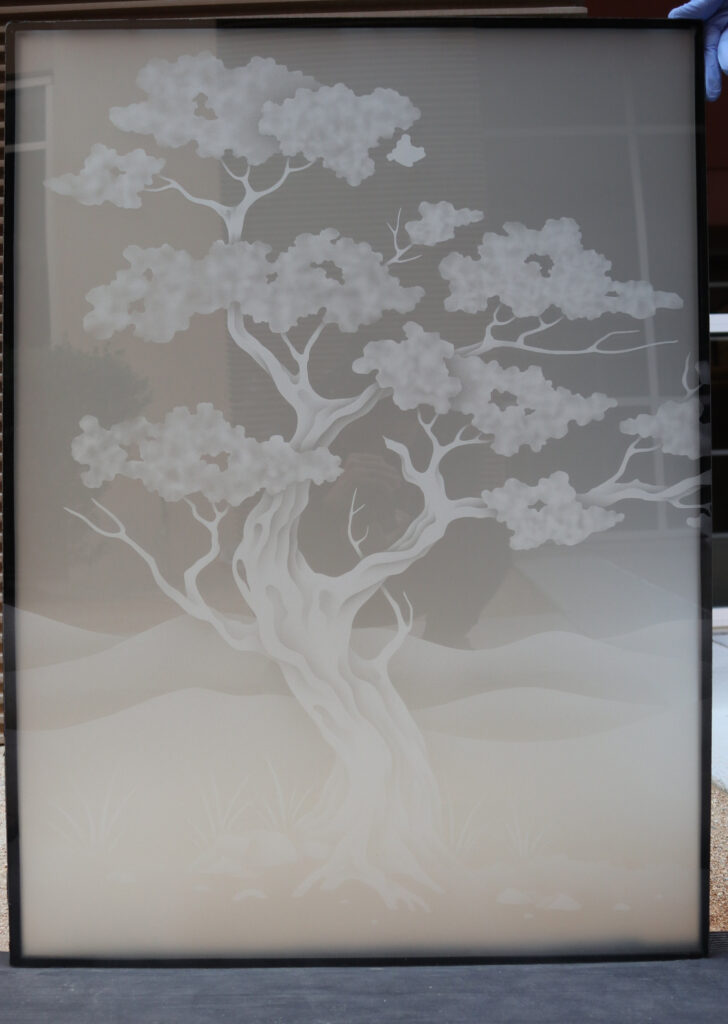 Frosted Bonsai glass partition panel featuring a sculptural tree design and soft desert landscape background