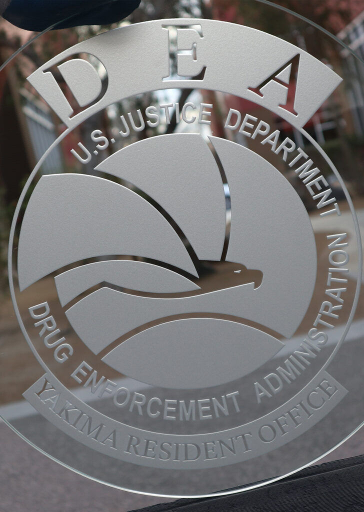 Etched glass panel featuring DEA seal with frosted design and detailed lettering, showcasing professional custom logo signage on clear glass