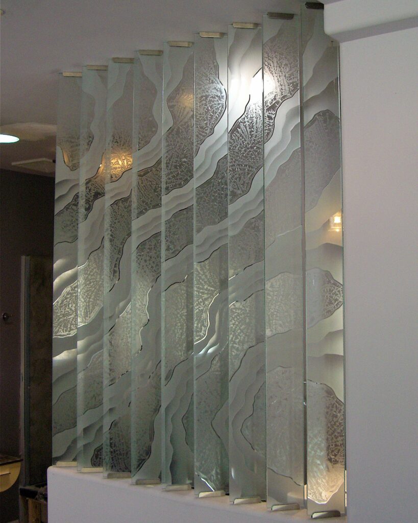 Glass partition wall with vertical glass panels and partial framing, featuring a frosted shoreline pattern for privacy and light.