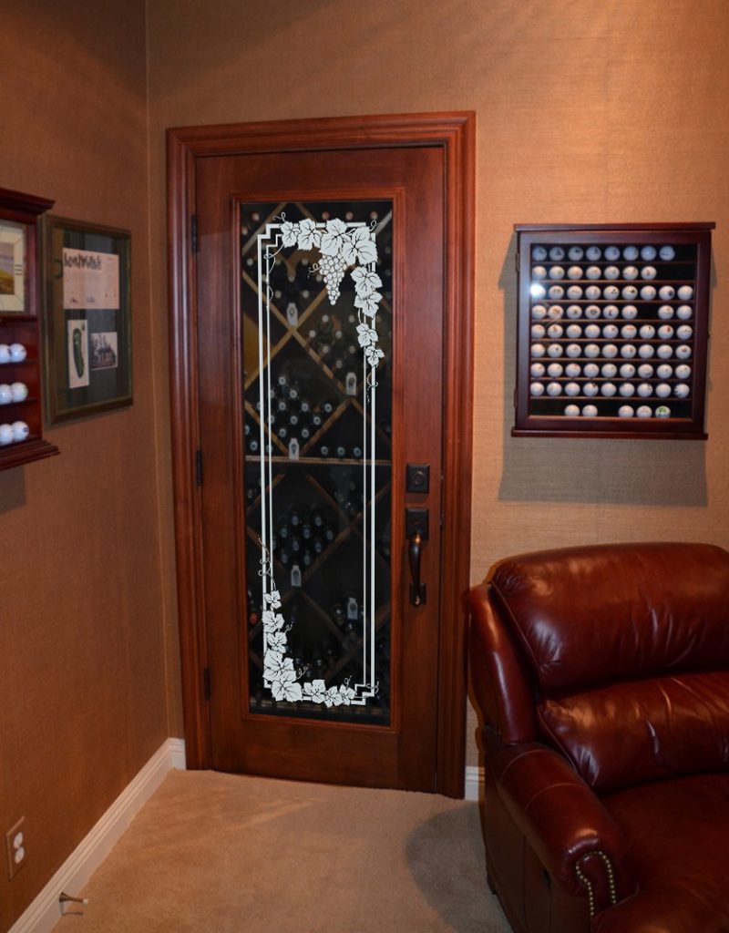 Vintage wood pantry door with clear glass insert featuring an etched grapevine border, styled like an antique wine cellar door