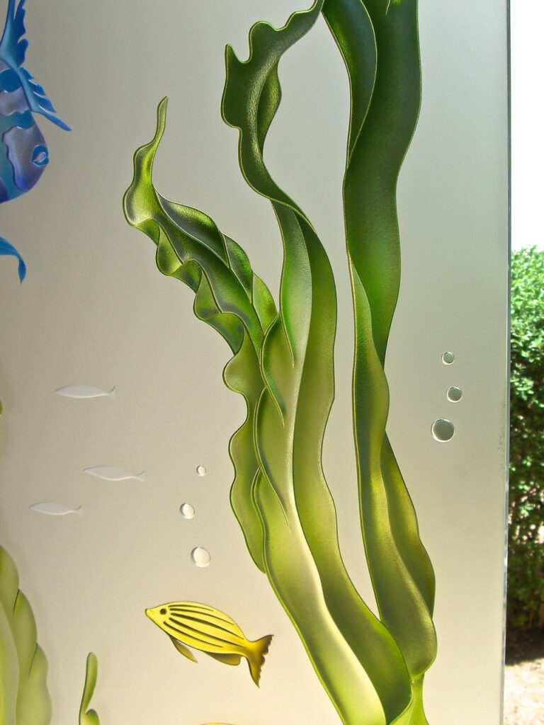 Close-up view of intricate 3D carved frosted glass depicting vibrant seaweed and playful fish, showcasing the stunning detail and depth of the design.
