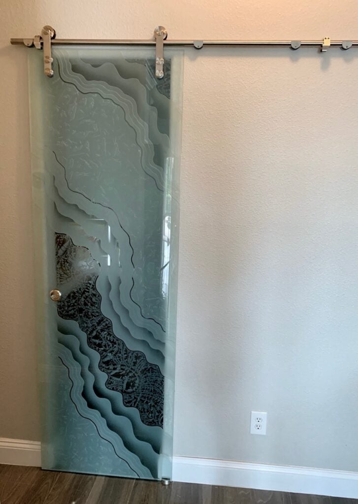 Modern frosted glass barn door with abstract carved wave design for small kitchen pantry space-saving solution