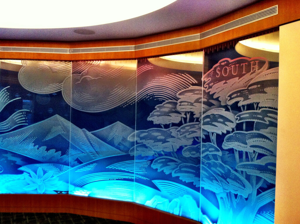 Backlit decorative glass wall partition with etched South-themed landscape design showing how controlled lighting can improve privacy and visual impact.