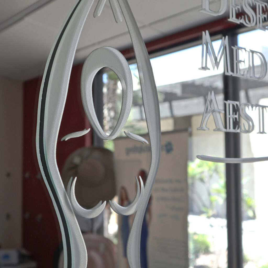 Decorative carved glass sign detail with dimensional logo and lettering, custom glass design highlighting texture and craftsmanship
