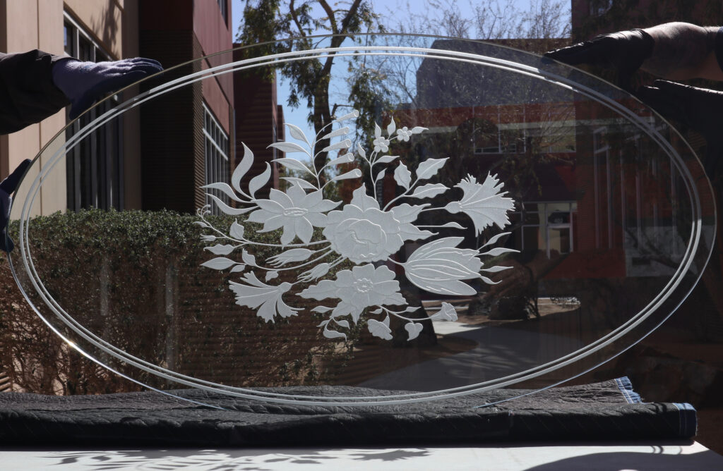 oval glass tabletop with frosted etched floral design featuring roses and leaves on clear glass