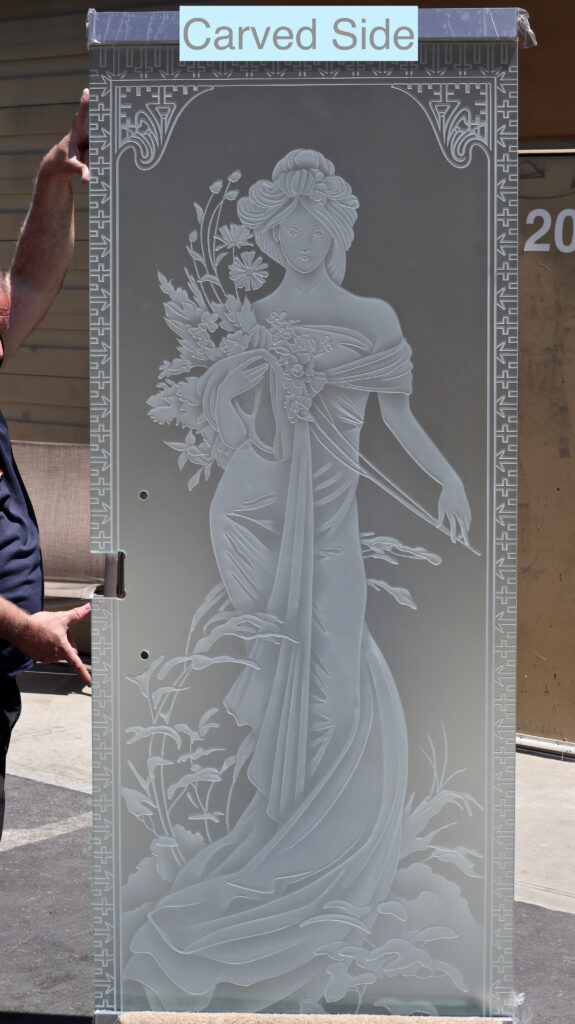 Custom 3D carved frosted glass door featuring an elegant woman and floral artwork, demonstrating Sans Soucie's advanced sculpture-carving techniques and multi-depth etched glass craftsmanship